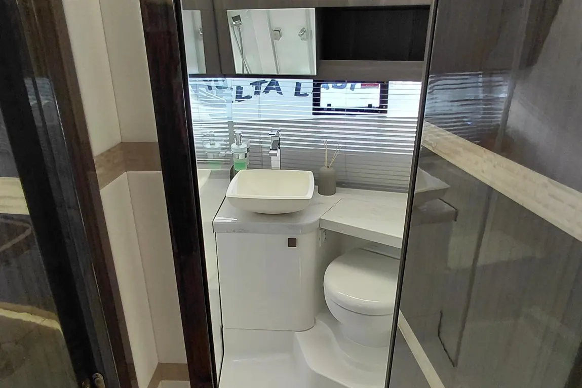Modern bathroom view featuring a white toilet, a square basin, and essential toiletries on a marble countertop.